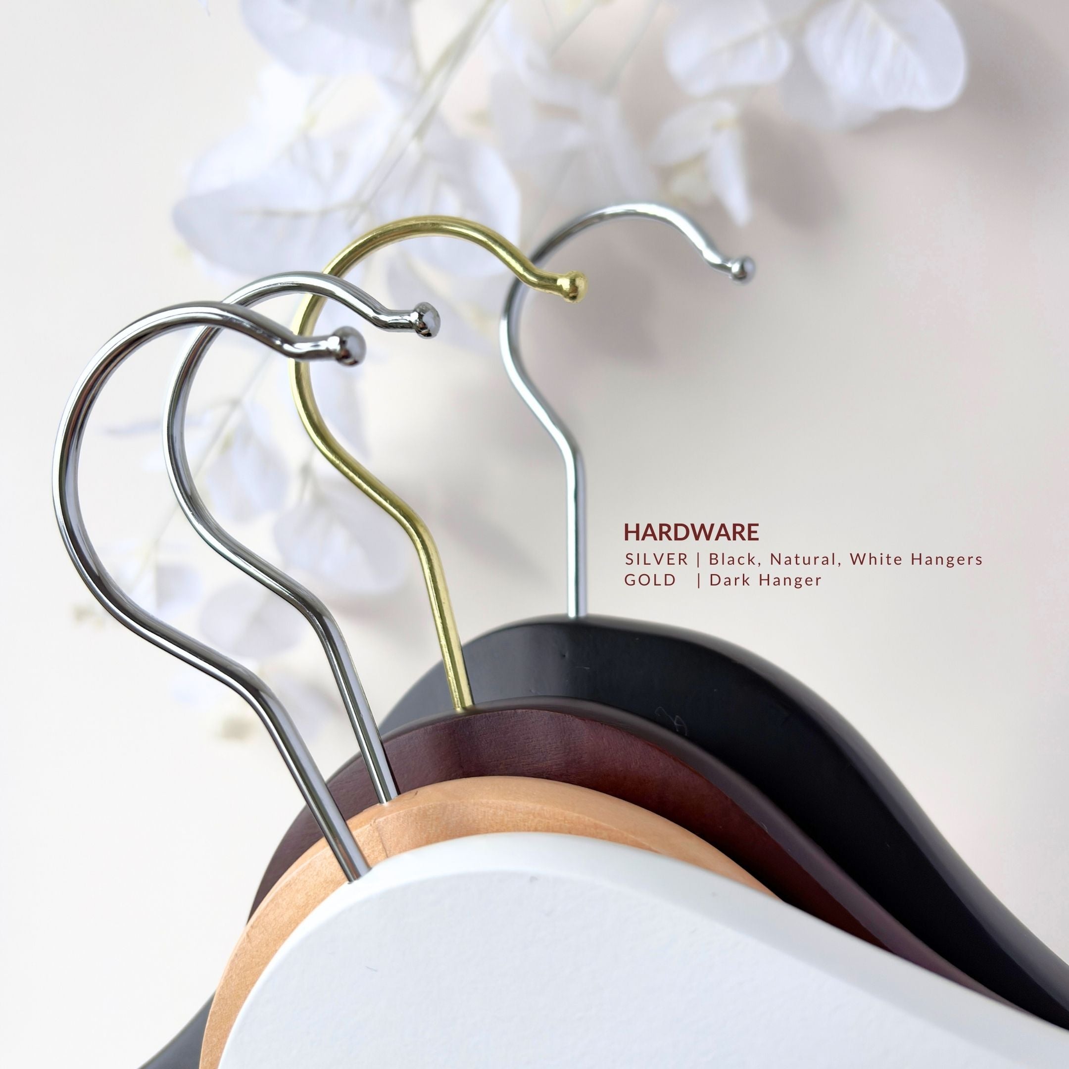 Set of hangers with different hardware finishes on a neutral background