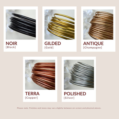 Five wire coil samples in different finishes on a beige background