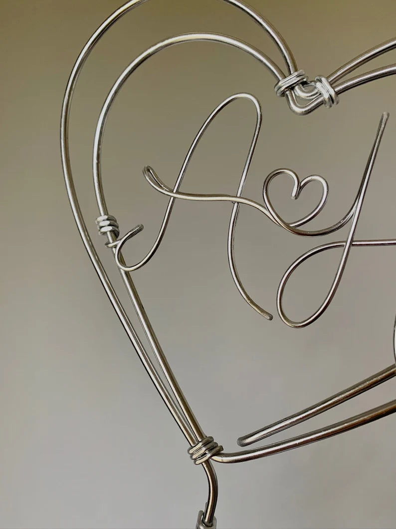 a close up detail of a silver wire heart cake topper, showing handcrafted quality