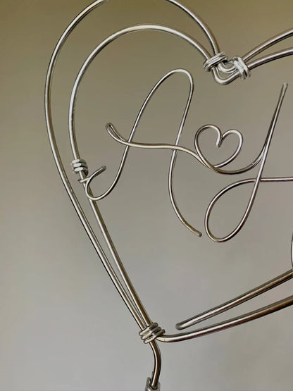 a close up detail of a silver wire heart cake topper, showing handcrafted quality